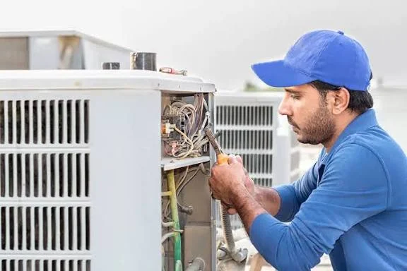 Technician repairing electrical components inside HVAC equipment