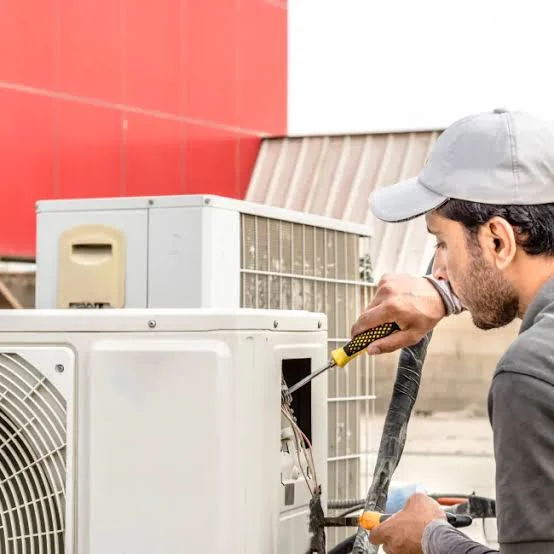 Technician inspecting air conditioning equipment for reliable airflow
